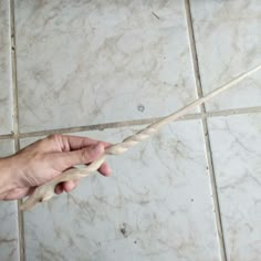 a hand holding a rope on top of a tile floor