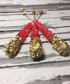 three pieces of gold and red beaded jewelry on wooden boards with pins in the middle