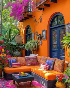 an orange couch sitting on top of a colorful rug in front of a building with potted plants