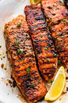 grilled salmon with lemon wedges on a white plate