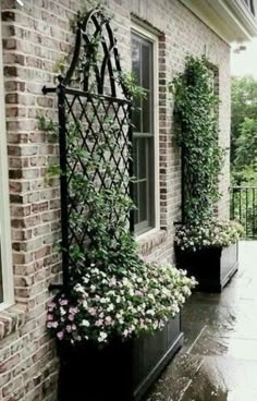 two black planters filled with flowers on the side of a brick building next to a door