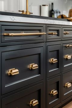 a kitchen with black cabinets and gold pulls on the handles, drawers and cupboards