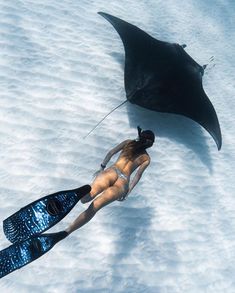 a woman is floating in the snow with an umbrella and snorkels on her feet