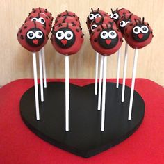 cake pops with ladybugs on them sitting on top of a heart shaped plate