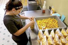 a woman standing in front of a tray filled with popcorn