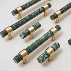 eight green marble and gold - plated handles on white surface with one in the middle