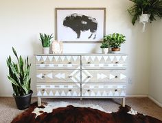 a white dresser sitting next to a potted plant