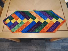 a multicolored table runner sitting on top of a wooden table