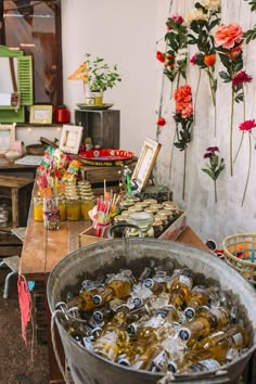 there is a bucket full of sodas on the table with flowers in the background