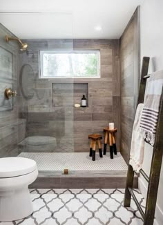 a white toilet sitting in a bathroom next to a walk in shower and wooden ladder