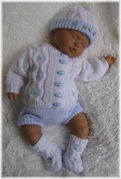 a baby doll is laying on a white blanket