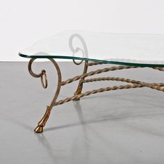 a glass and metal coffee table sitting on top of a white floor