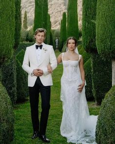 a man in a tuxedo and a woman in a wedding dress standing next to each other