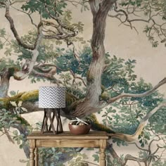 a table with a lamp on it in front of a tree wallpapered background