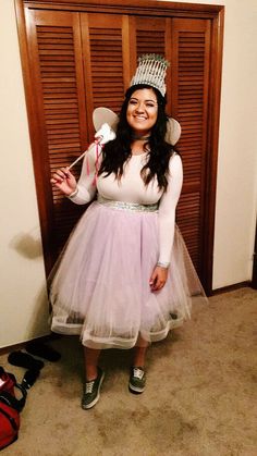 a woman in a tulle skirt and tiara poses for a photo while holding a pair of scissors