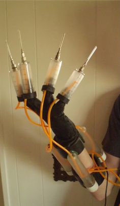 a man holding three sys in his arms with orange cords attached to the arm