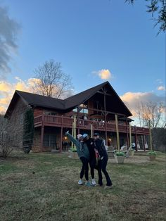 two people standing in front of a house with their arms around each other while the sun is setting