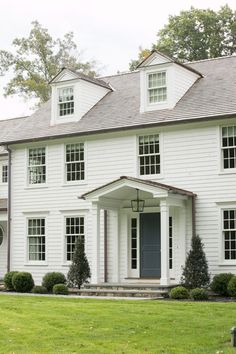 a large white house sitting on top of a lush green field