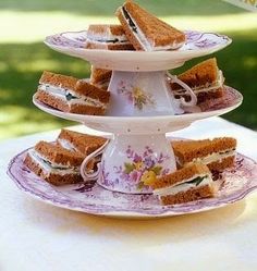 there is a cake stand with sandwiches on it