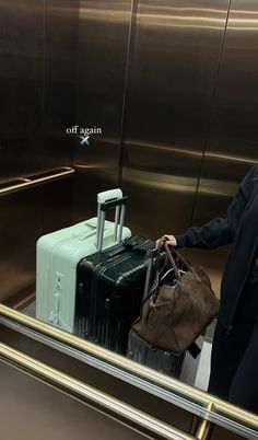 a man is standing in an elevator with two suitcases and a bag on his shoulder