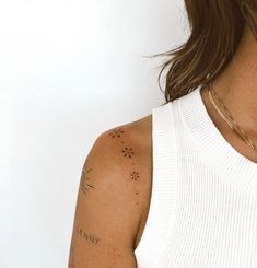 a woman wearing a white tank top with tattoos on her arm