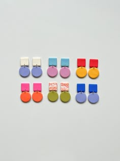 several pairs of colorful earrings on a white surface with clippings attached to them