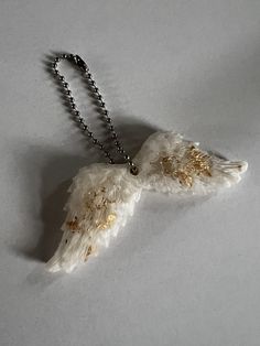 an angel wing with gold flecks is on a ball chain