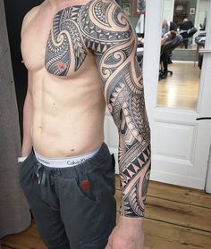 a man with a tattoo on his arm and chest standing in front of a door