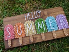 the word hello summer spelled out in crochet on a wooden board with popsicle sticks