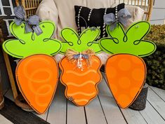 three carrot shaped cut outs sitting on top of a wooden floor next to a chair