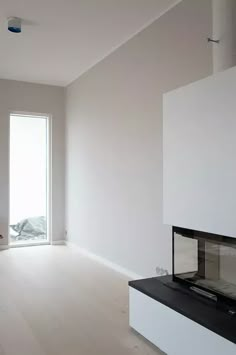 an empty living room with white walls and wood flooring on the far wall is a fireplace