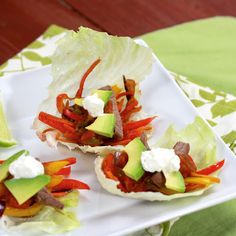 three lettuce cups filled with meat, peppers and avocado on a white plate