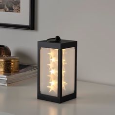 a black lantern with white stars on it sitting on top of a table next to a stack of books