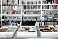 the shelves are filled with many books and magazines in glass bins on top of them