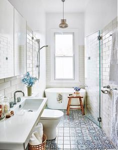 a bathroom with blue and white tiles on the floor, sink, toilet and bathtub