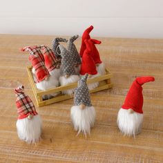 four gnomes sitting on top of a wooden table with red and white hats around them