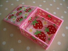 two pink boxes with strawberry designs on them sitting on a polka dot covered tablecloth