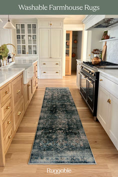 a kitchen with white cabinets and wood floors has a blue runner rug on the floor