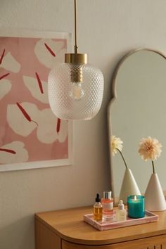 a vanity with a mirror, vases and bottles on it in front of a pink wall