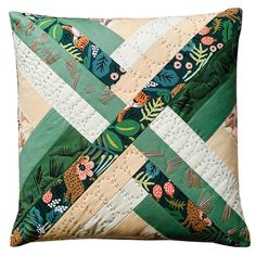 a green and white quilted pillow with an animal design on the front, along with leaves and flowers