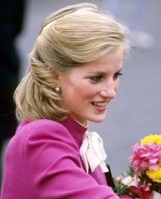 a woman in a pink jacket holding flowers