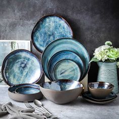 a table topped with plates and bowls next to a vase