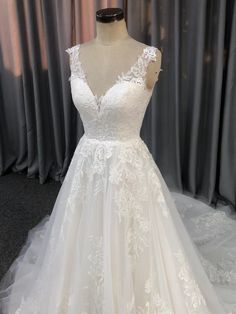 a white wedding dress on display in front of curtains