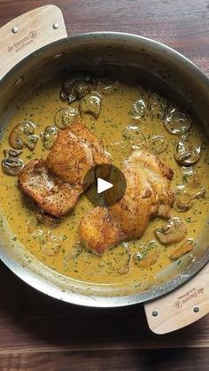 a pan filled with chicken and mushrooms on top of a wooden table