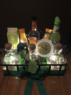 an assortment of alcohol bottles and glasses in a glass container with a green ribbon around it