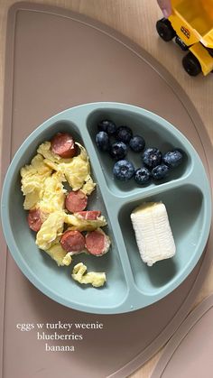 a child's plate with blueberries, eggs, and sausages on it