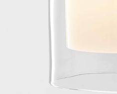 a lit candle in a clear glass container on a white background with the light turned off