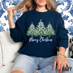 a woman sitting on a couch wearing a merry christmas sweatshirt