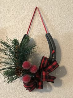 a red and black bow hanging from a hook with pine cones on the handle,