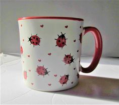 a red and white coffee cup with ladybugs on it